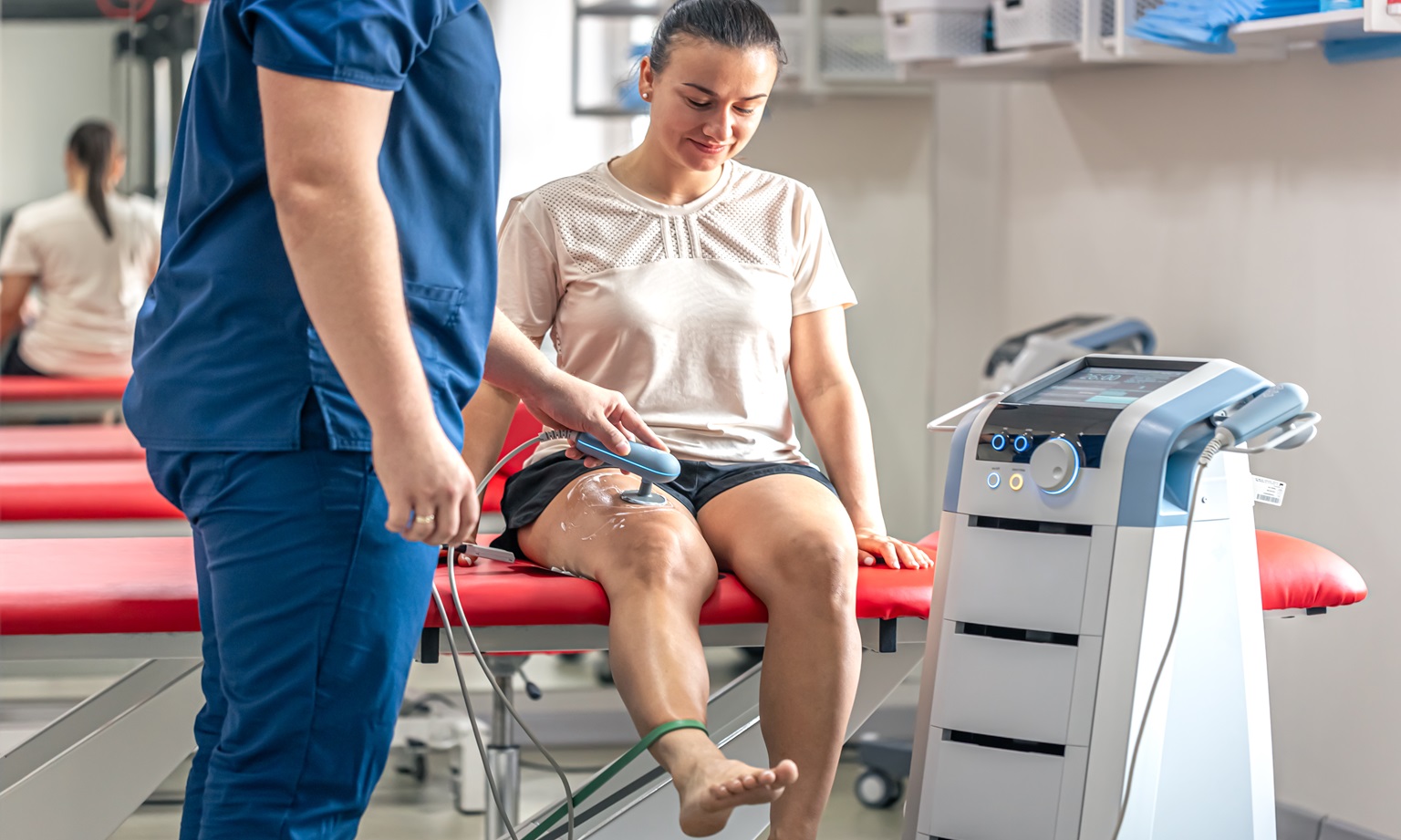 Doctor using machine to treat the knee joints of a patient, T-CaRe technology, resistive and Capacitive therapy.